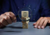 Man holding a magnifying glass to look at wooden blocks with law or legal symbol.