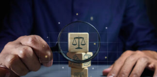 When Remote Work Reaches A Jury, Flexibility Wins Man holding a magnifying glass to look at wooden blocks with law or legal symbol.