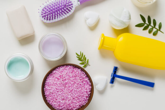 Overhead view pink salt with cosmetics products white background