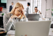 The Hidden Rebellion Against RTO and for Well-Being Stressed businesswoman holding her head in pain and having headache at work.