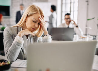 The Hidden Rebellion Against RTO and for Well-Being Stressed businesswoman holding her head in pain and having headache at work.