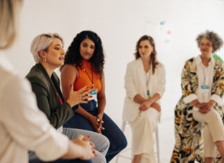 How Girl Hold My Hand Reflects Stormy Nicole Wellington’s Larger Mission Confident businesswomen having a discussion during a conference meeting. Group of multicultural businesswomen sharing ideas while working together in an all-female startup.