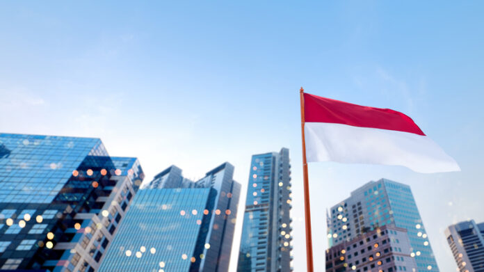 Closeup view of the Indonesian national flag waving with skyscrapers and a blue sky background. Celebrate Indonesia Independence Day. Concept of Kemerdekaan Indonesia Indonesia leadership