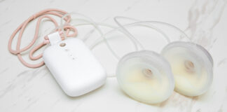 Smart pumping: Electric breast pump with milk collection cups on a white marble background.