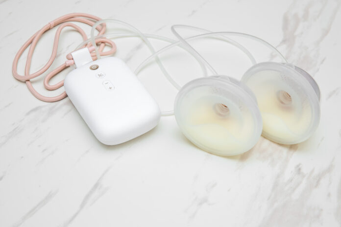 Electric breast pump with milk collection cups. Smart pumping: Electric breast pump with milk collection cups on a white marble background.