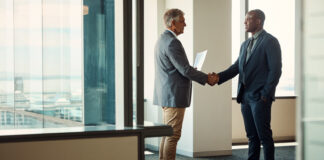 Full length shot of two businessmen shaking hands in an office for global business