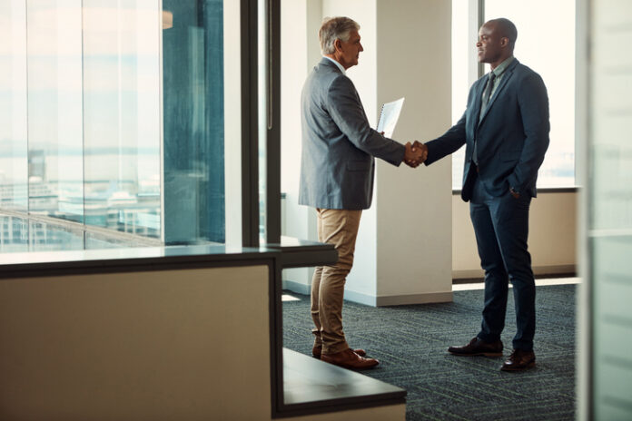 Full length shot of two businessmen shaking hands in an office for global business