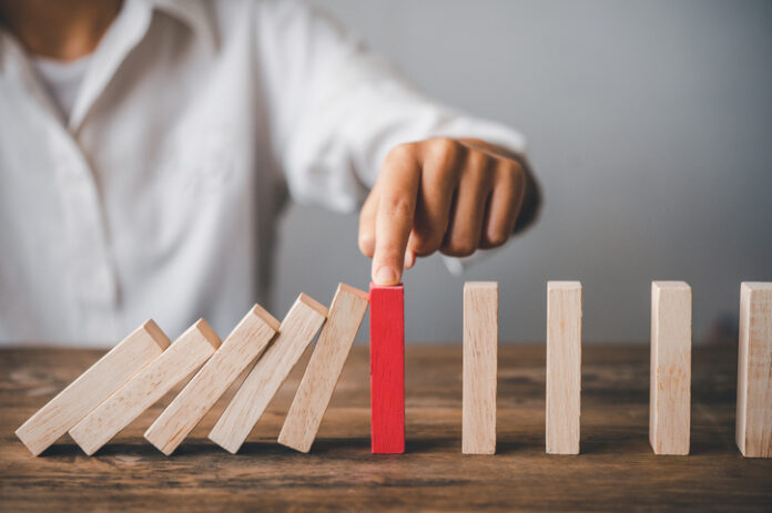 close-up hand The hand of a businessman who is stopping or preventing a falling block.Risk protection concept,Eliminating the risk. Despute prevention
